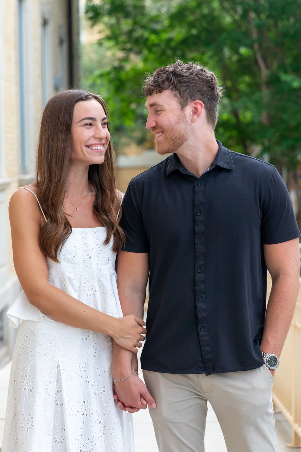 Raney and Austin holding hands and laughing on a sidewalk