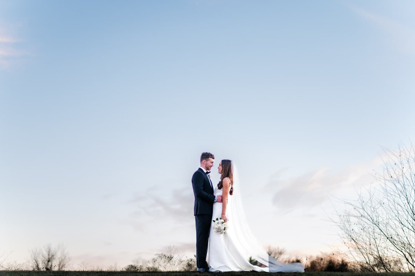 Raney and Austin at their wedding under a wide evening sky